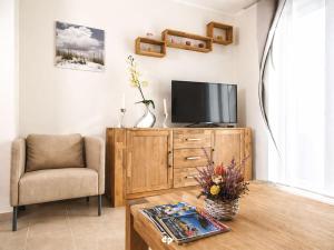 a living room with a tv and a chair and a table at DUENENZEIT App Nr 5 max 4 Pers in Dierhagen