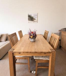 a wooden table with chairs and a vase of flowers on it at DUENENZEIT App Nr 5 max 4 Pers in Dierhagen