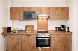 a kitchen with wooden cabinets and a microwave at DUENENZEIT App Nr 5 max 4 Pers in Dierhagen +4 photos