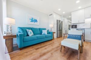 a living room with a blue couch and a kitchen at Tide Time Oceanfront at Sea Cabin w Pool in Myrtle Beach +42 photos