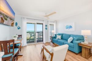 a living room with a blue couch and a table at Tide Time Oceanfront at Sea Cabin w Pool in Myrtle Beach