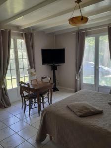 ein Schlafzimmer mit Bett, Tisch und Fernseher in der Unterkunft L'Ariade in Monpazier