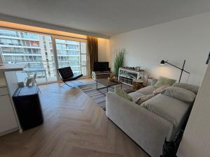 a living room with a couch and a large window at Beachday II - Opkuis inbegrepen in de prijs - Garagebox inbegrepen in Nieuwpoort