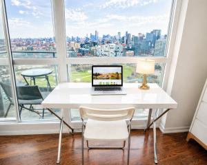 a white table with a laptop on it in front of a window at 2 Bedroom Condo With City Views and Free Parking in Toronto +5 photos