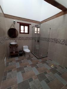 a bathroom with a toilet and a glass shower at Hotel Santa Barbara Sachica in Villa de Leyva