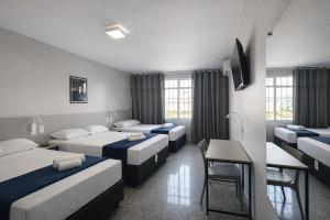 a hotel room with four beds and a desk at Vértice Hotel in Brasília