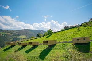 a green hill with houses on top of it at Cabanas do Navia in Coea