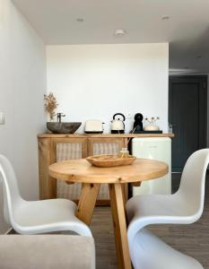 a kitchen with a wooden table and white chairs at G A Suites Maisonettes in Skala in Skala
