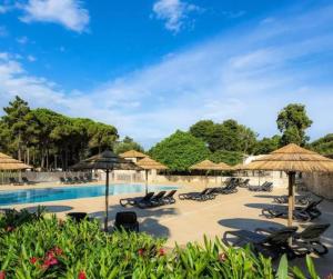 a resort with a pool and chairs and umbrellas at Cottage PARKS DI LICCIA in Bonifacio