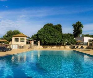 a large blue swimming pool with a house in the background at Cottage PARKS DI LICCIA in Bonifacio
