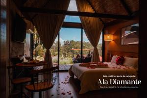 a bedroom with a bed and a large window at Pousada das Pedras in Monte Verde