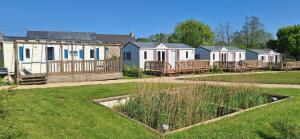 a row of mobile homes in a yard with grass at Ecuries Leseigneur - Camping Insolites in Bolleville
