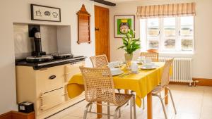 a kitchen with a table with a yellow table cloth at Lower Farmhouse in Todenham