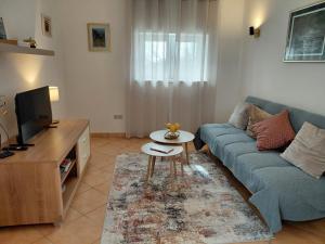 ein Wohnzimmer mit einer blauen Couch und einem Fernseher in der Unterkunft Joy4You in Čilipi