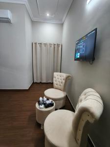 a room with two chairs and a table and a tv at Oasis Family Hotel in Lahore