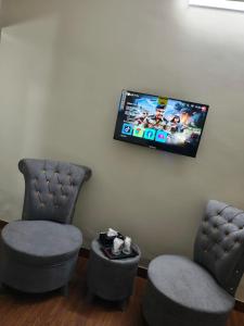 two chairs and a flat screen tv on a wall at Oasis Family Hotel in Lahore