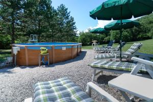 a group of chairs and a hot tub with umbrellas at Chalet D'alpion Nord avec Piscine in Les Tourrettes