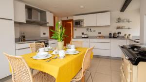 a dining room with a yellow table and chairs in a kitchen at Lower Farmhouse in Todenham +24 photos