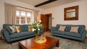 a living room with two blue couches and a table at Lower Farmhouse in Todenham