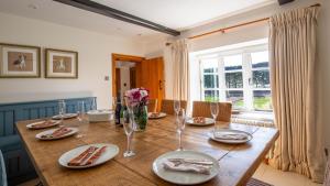a dining room table with plates and glasses on it at Lower Farmhouse in Todenham