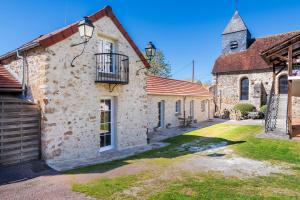 an old stone building with a balcony and a church at La Maisonnette de Marguerite - Avec Climatisation in Vendières