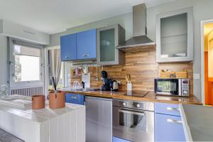 a kitchen with blue cabinets and a microwave at Entre Dunes et Forêt - Proche Plage in Cucq