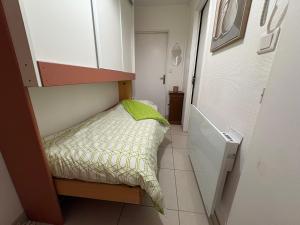 a small bedroom with a bed with a green pillow at Entre Dunes et Forêt - Proche Plage in Cucq