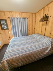 a bedroom with a bed in a room with wooden walls at 2BR 1BA Cabin #7 Riverside Point Resort in Park Rapids