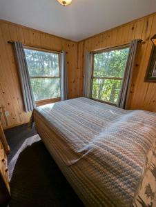 a bedroom with two windows and a bed in it at 2BR 1BA Cabin #7 Riverside Point Resort in Park Rapids