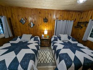 two beds in a room with wooden walls at Cozy Studio Cabin #5 Riverside Point Resort in Park Rapids