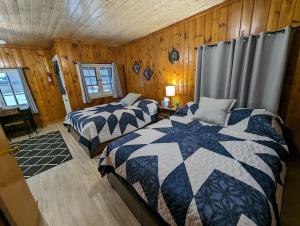 two beds in a room with wooden walls at Cozy Studio Cabin #5 Riverside Point Resort in Park Rapids