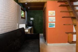 a living room with a couch and an orange wall at Chale 1 com Churrasqueira e Ar a 200m da Praia in Prado