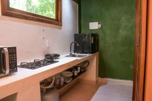 a kitchen with a sink and a stove and a microwave at Chale 1 com Churrasqueira e Ar a 200m da Praia in Prado +27 photos