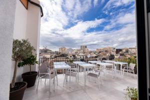 a balcony with tables and chairs and a view of the city at Riflessi Acireale Palace Suites in Acireale