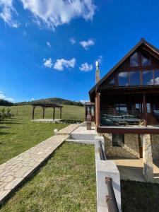 a building with a stone walkway next to a field at Zlatibor Sky Inn in Zlatibor
