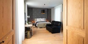 a bedroom with a bed and a black leather chair at B&B Scheldekant in Oudenaarde