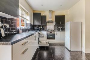 a kitchen with white appliances and black tile floors at 4BD Spacious detached House in Birmingham suitable for Contractors and family's with free parking on private drive sleeps 9 in Birmingham
