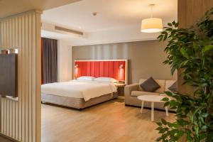 a hotel room with a bed and a couch at Park Inn by Radisson Bucharest Hotel & Residence in Bucharest +86 photos