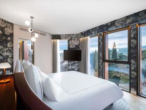 a bedroom with a large white bed and large windows at Swissôtel Tbilisi in Tbilisi City +149 photos