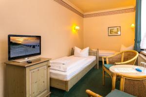 a hotel room with a bed and a television at Hotel Sonneneck in Zinnowitz
