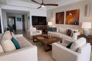 a living room with white furniture and a flat screen tv at The Cliff View in Cupecoy