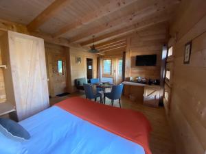 a bedroom with a bed and a table with chairs at Les Cabanes Dans Les Bois Logis Hôtel in Villalier
