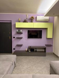 a living room with a purple wall with a tv at La casa nel parco in Chieri +1 photo