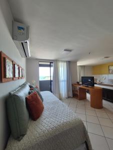 a bedroom with a bed and a desk and a kitchen at NATAL PLAZA PONTA NEGRA in Natal