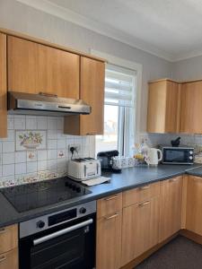 a kitchen with wooden cabinets and a stove top oven at 2A Lochy Crescent in Inverlochy