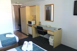a hotel room with a desk and a television at Rocky Glen Hotel Motel Gladstone in Gladstone