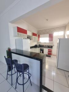 a kitchen with a black counter and two chairs at Bela Casa PX as praias in São Luís