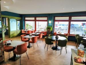 a restaurant with tables and chairs and windows at Albium Hotel in Albenga