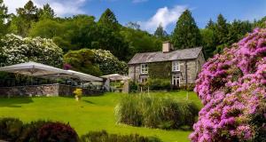 a house with pink flowers in the yard at Aberdunant Hall Holiday Park, Snowdonia in Porthmadog