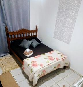 a small bedroom with a bed with a flowery blanket at Harmonia Studio Mobiliado in Campo Grande